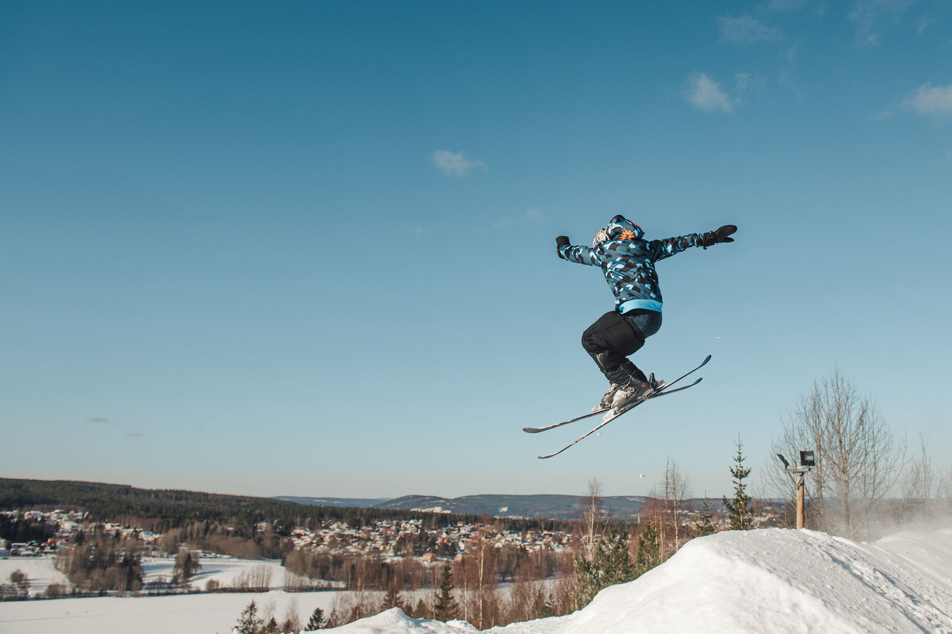 Fotografi av en kille som hoppar med sina skidor i en slalombacke.