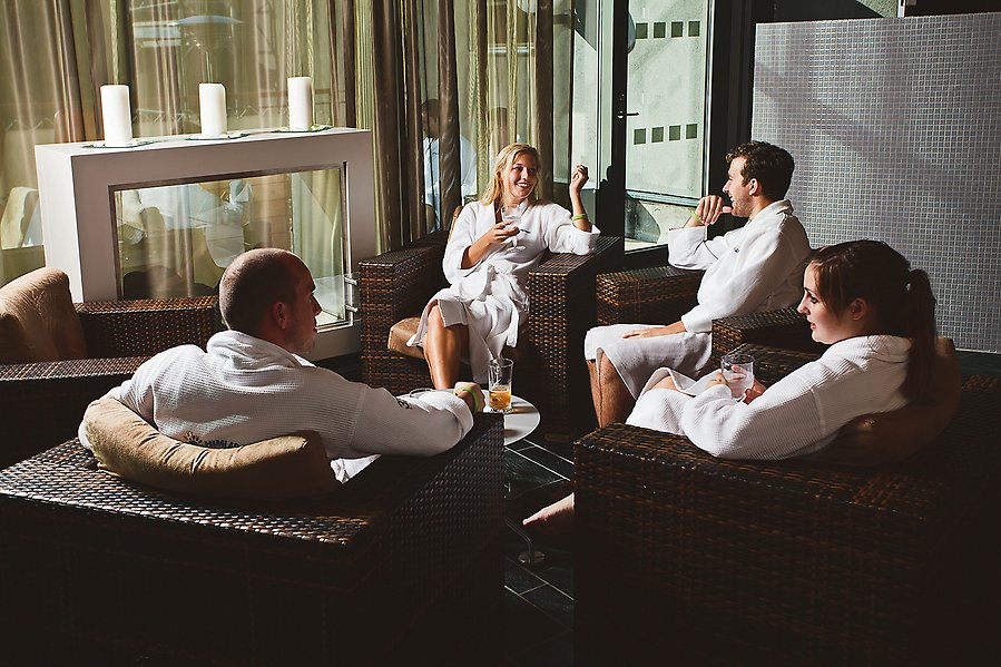Foto av fyra personer som sitter i fåtöljer. Alla har vita badrockar på sig.