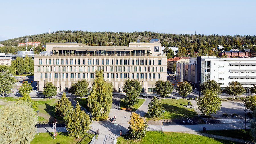 drönarfoto över hotell Clarion i Sundsvall. i förgrunden ser man en gångbana, och ett parkområde med träd. I mitten av bilden ser man byggnaden av Clarion Hotell. Bakom byggnaden ser man Norra Berget.